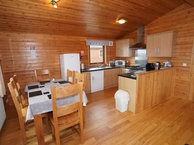 a kitchen with a dining table and a kitchen with wooden walls at Chalet Loch Leven Lodge 11 by Interhome in Kinross