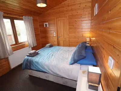 a bedroom with a bed in a wooden cabin at Chalet Loch Leven Lodge 11 by Interhome in Kinross