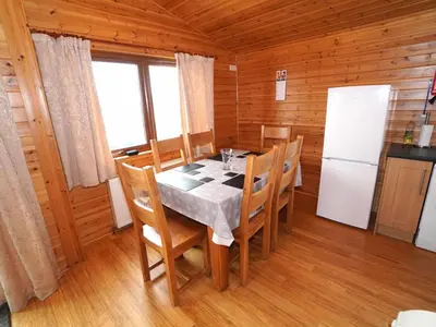 a dining room with a table and chairs and a refrigerator at Chalet Loch Leven Lodge 11 by Interhome in Kinross
