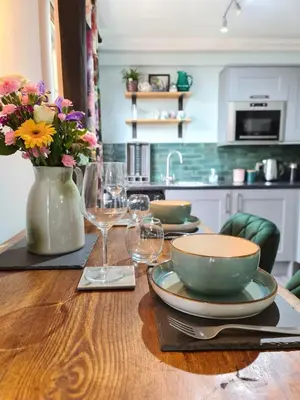 a table with plates and glasses and a vase with flowers at EDEN Apartment, Oban in Oban