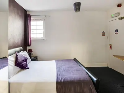 a bedroom with a bed with a purple pillow at OYO Gin House Hotel in Greenock