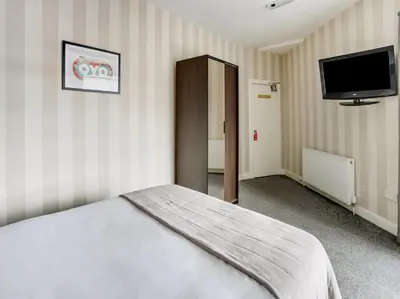 a bedroom with a bed and a flat screen tv at OYO Gin House Hotel in Greenock