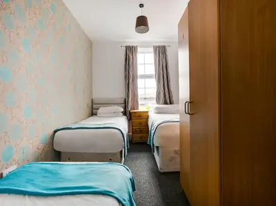 a small room with three beds and a window at OYO Gin House Hotel in Greenock