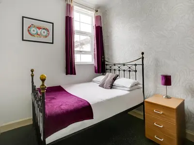 a bedroom with a bed with purple sheets and a window at OYO Gin House Hotel in Greenock