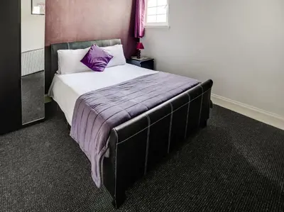 a bedroom with a bed with a purple blanket on it at OYO Gin House Hotel in Greenock