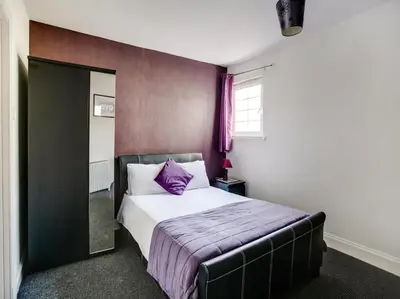 a bedroom with a large bed with a purple blanket at OYO Gin House Hotel in Greenock
