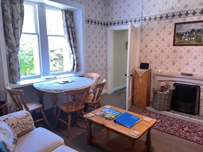 a living room with a table and a fireplace at Laundry Cottage in Lanark
