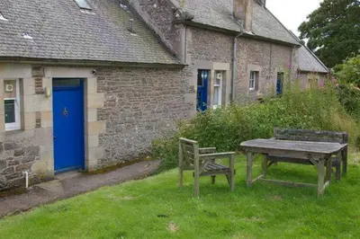 a picnic table and bench in front of a building at Laundry Cottage in Lanark