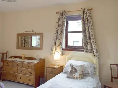 a bedroom with a bed with a dresser and a window at Cluniter Cottage in Innellan