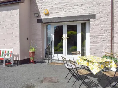 a patio with a table and chairs in front of a door at Cluniter Cottage in Innellan
