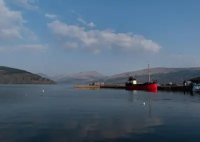 a red boat is docked in a body of water at Inveraray Hostel in Inveraray