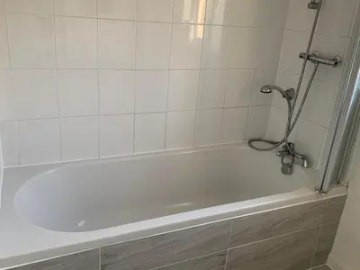 a white bath tub in a white tiled bathroom at Dada House in Glasgow