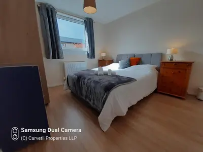 a bedroom with a bed and a dresser and a window at Carvetii - Stuart House - 1st floor flat sleeps up to 8 in Falkirk