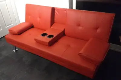 an orange couch with two controllers on it at The Cottage - Hot Tub - nr Glasgow - self check-in in Coatbridge