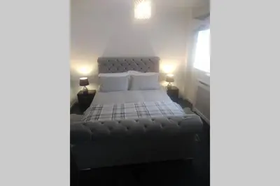 a bedroom with a large bed with white sheets and pillows at The Cottage - Hot Tub - nr Glasgow - self check-in in Coatbridge