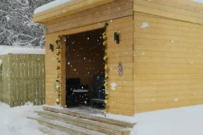 a wooden cabin with a door in the snow at The Cottage - Hot Tub - nr Glasgow - self check-in in Coatbridge
