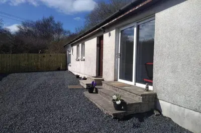 a house with potted plants next to a window at The Cottage - Hot Tub - nr Glasgow - self check-in in Coatbridge