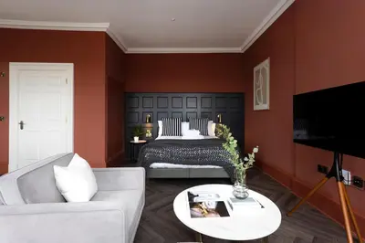 a living room with a bed with red walls at 29 Queen Street Aparthotel in Edinburgh
