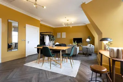 a dining room with yellow walls and a table and chairs at 29 Queen Street Aparthotel in Edinburgh