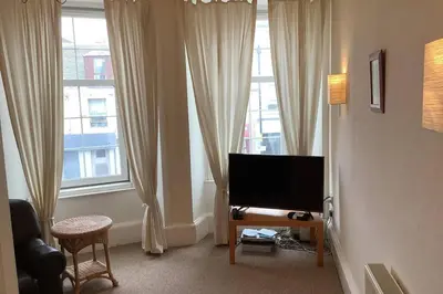 a living room with a flat screen tv and windows at Ferry View in Largs
