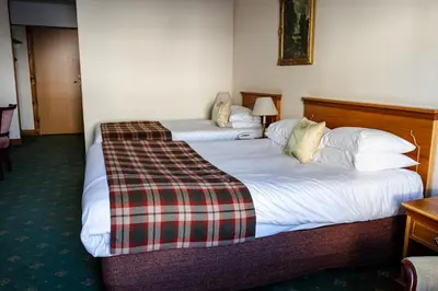 two beds in a hotel room with a plaid blanket on them at North West Castle Hotel in Stranraer