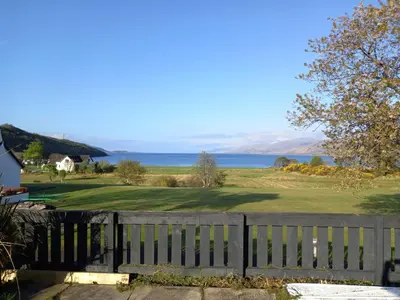 a view of the ocean from behind a fence at Taigh Mara(Marine House) 2 bed Apartment in Fort William