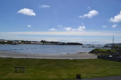 a bench sitting on the grass near a body of water at Eilidh’s Guest House in Port Ellen