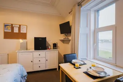 a bedroom with a bed and a desk and a window at Eilidh’s Guest House in Port Ellen