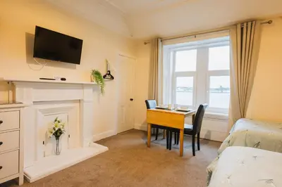 a room with a table and a bed and a bed and a room with at Eilidh’s Guest House in Port Ellen