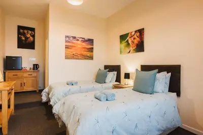 a bedroom with two beds and a desk and a tv at Eilidh’s Guest House in Port Ellen