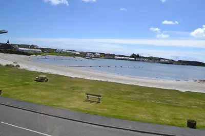 a view of a beach with a bench on the grass at Eilidh’s Guest House in Port Ellen