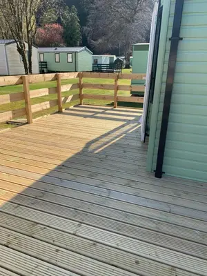 a wooden deck next to a house with a fence at The Roecliffe 54 in Dunoon