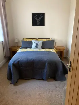 a bedroom with a blue bed with two tables at Fantastic Cottage in Loch Lomond National Park in Alexandria