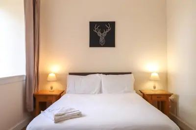 a bedroom with a white bed with two night stands at Fantastic Cottage in Loch Lomond National Park in Alexandria