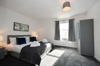 a bedroom with a bed with blue pillows and a window at Mews House in Ayr