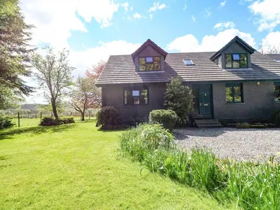 a house with a grassy yard in front of it at Upper Brackendale in Taynuilt