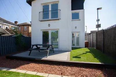 a white house with a bench in front of it at Southside Flat with Private Garden! in Glasgow