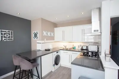 a kitchen with white cabinets and a black counter top at Southside Flat with Private Garden! in Glasgow