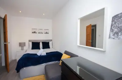a bedroom with a bed and a mirror and a couch at Southside Flat with Private Garden! in Glasgow