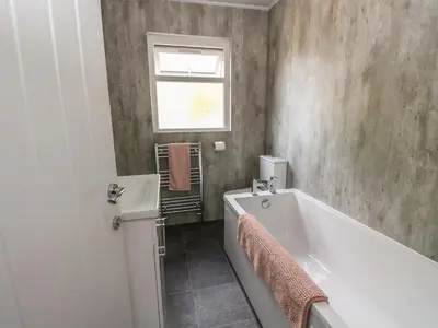 a bathroom with a tub and a sink and a window at Innishail in Lochgilphead