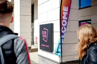 a man and woman walking past a sign in a building at Canvas Glasgow in Glasgow