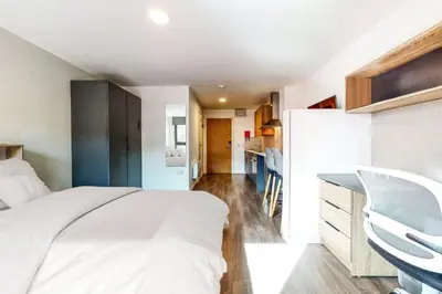 a bedroom with a white bed and a kitchen at Canvas Glasgow in Glasgow