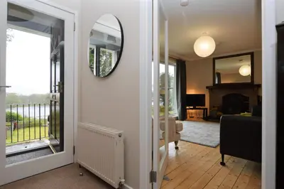 a hallway with a mirror and a living room at Nursery Cottage in Kilmun