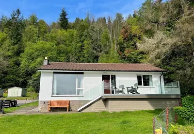 a small white house with a patio in a yard at Nursery Cottage in Kilmun