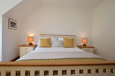 a bedroom with a large bed with two lamps at High Beach Cottage in Kames