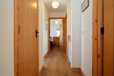 a hallway of a house with wooden floors and doors at High Beach Cottage in Kames