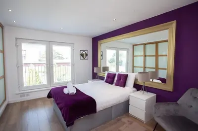 a bedroom with a large bed with purple walls at Mosspark Boulevard Exec Apartment ii - Free Parking in Glasgow