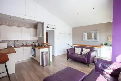a kitchen and a living room with a purple couch at Mosspark Boulevard Exec Apartment ii - Free Parking in Glasgow