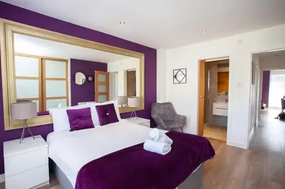 a bedroom with a large bed with purple walls at Mosspark Boulevard Exec Apartment ii - Free Parking in Glasgow
