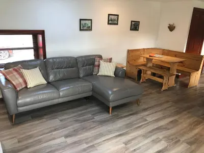 a living room with a leather couch and a wooden table at Maberry Cottage in Bargrennan
